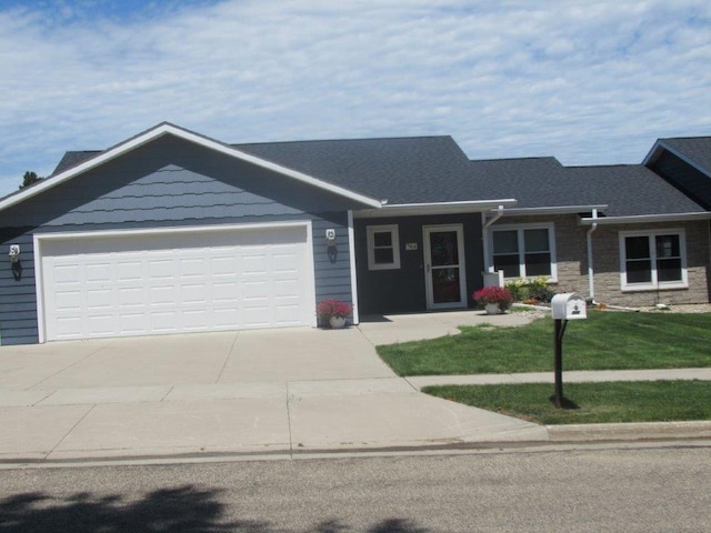 view of front of property featuring stone siding, concrete driveway, a front yard, a shingled roof, and a garage