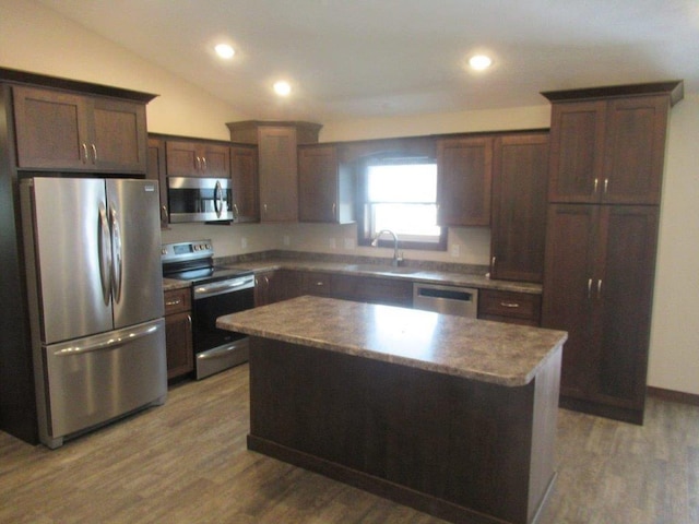 kitchen with a center island, lofted ceiling, appliances with stainless steel finishes, hardwood / wood-style floors, and sink