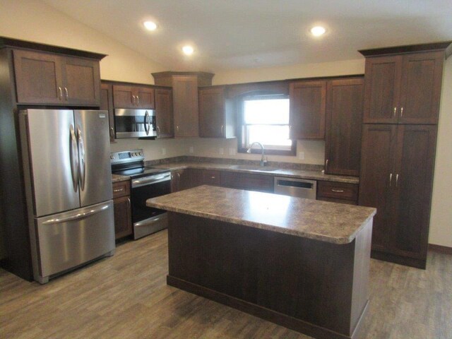 kitchen featuring appliances with stainless steel finishes, sink, a kitchen island, and hardwood / wood-style floors