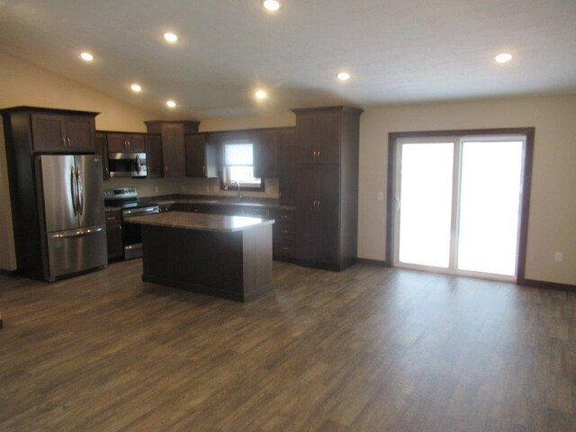 kitchen with dark hardwood / wood-style floors, stainless steel appliances, vaulted ceiling, and a kitchen island