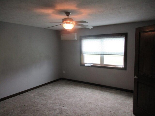 carpeted empty room featuring ceiling fan and a wall mounted air conditioner