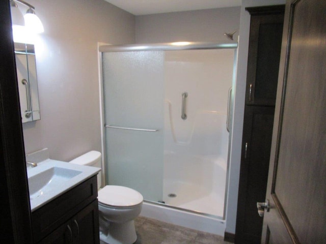 bathroom with a shower with shower door, vanity, toilet, and tile floors