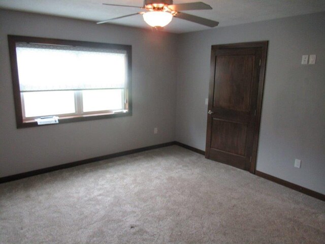 carpeted spare room featuring ceiling fan