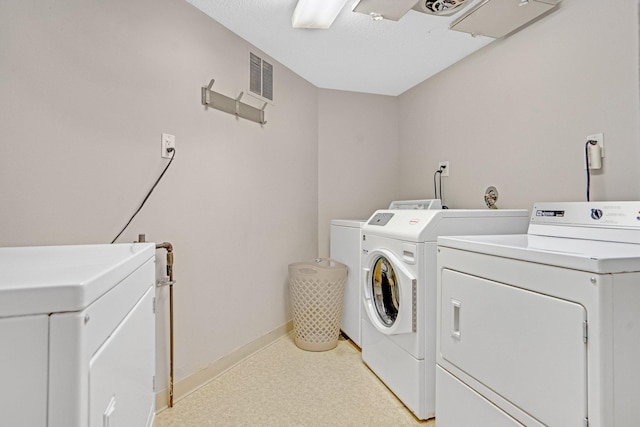 laundry room featuring washing machine and dryer, visible vents, and baseboards