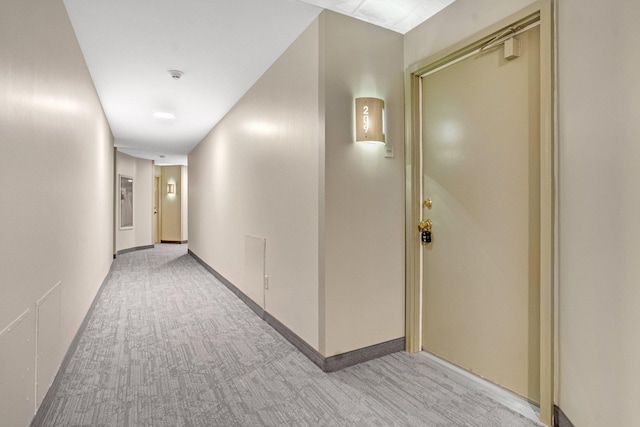 hall featuring light colored carpet and baseboards