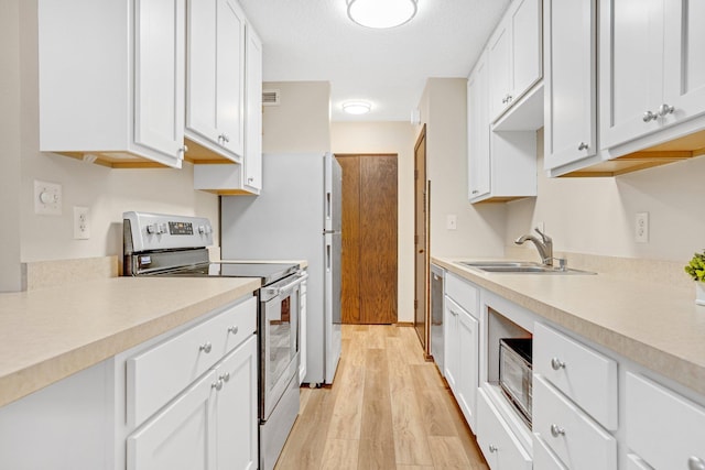 kitchen with appliances with stainless steel finishes, white cabinetry, and light hardwood / wood-style floors