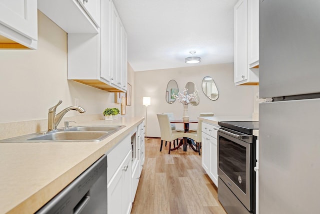 kitchen with light countertops, stainless steel appliances, light wood-style flooring, and a sink
