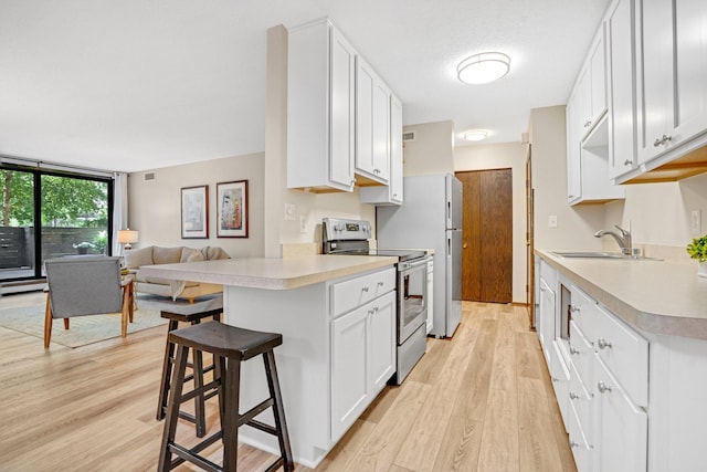 kitchen with stainless steel range with electric stovetop, white cabinetry, and sink