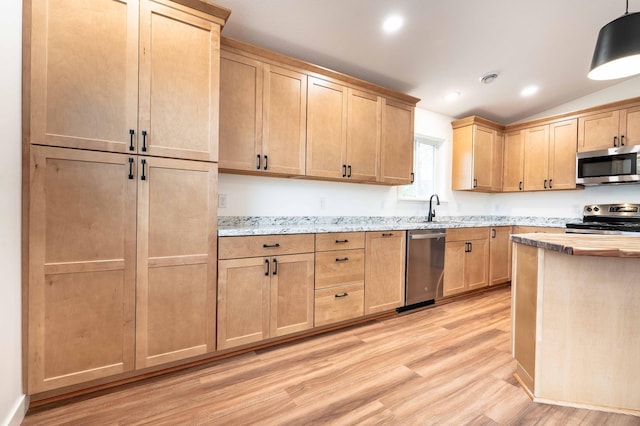 kitchen featuring light hardwood / wood-style flooring, hanging light fixtures, light stone countertops, vaulted ceiling, and appliances with stainless steel finishes