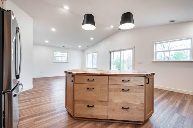 kitchen with a kitchen island, vaulted ceiling, stainless steel refrigerator, dark wood-type flooring, and decorative light fixtures