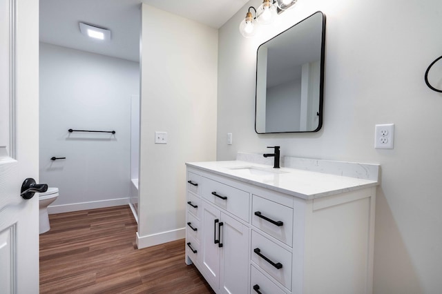 bathroom featuring vanity, a bathtub, hardwood / wood-style flooring, and toilet