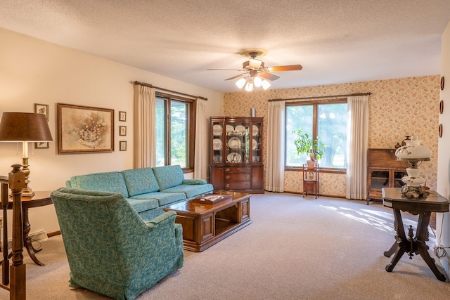 carpeted living room with a textured ceiling, ceiling fan, and a healthy amount of sunlight