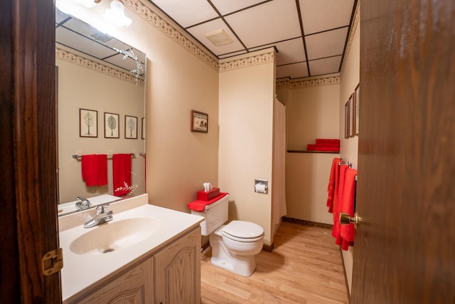 bathroom with a paneled ceiling, toilet, vanity, and hardwood / wood-style flooring