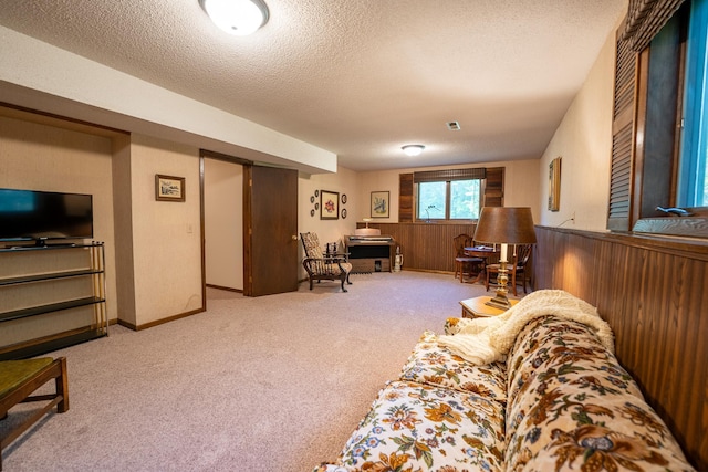 living room featuring a textured ceiling, light carpet, and wooden walls