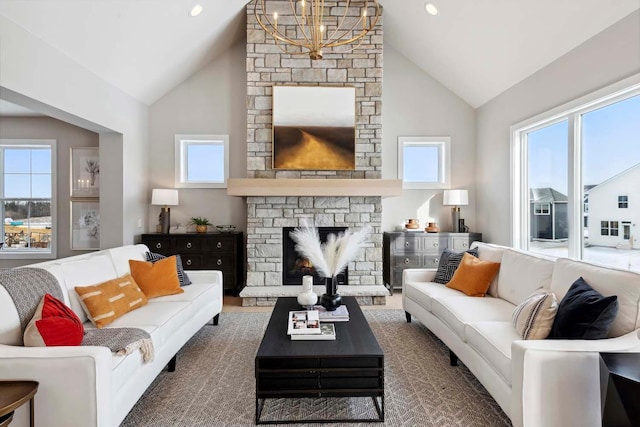 living room with a stone fireplace, a chandelier, and high vaulted ceiling