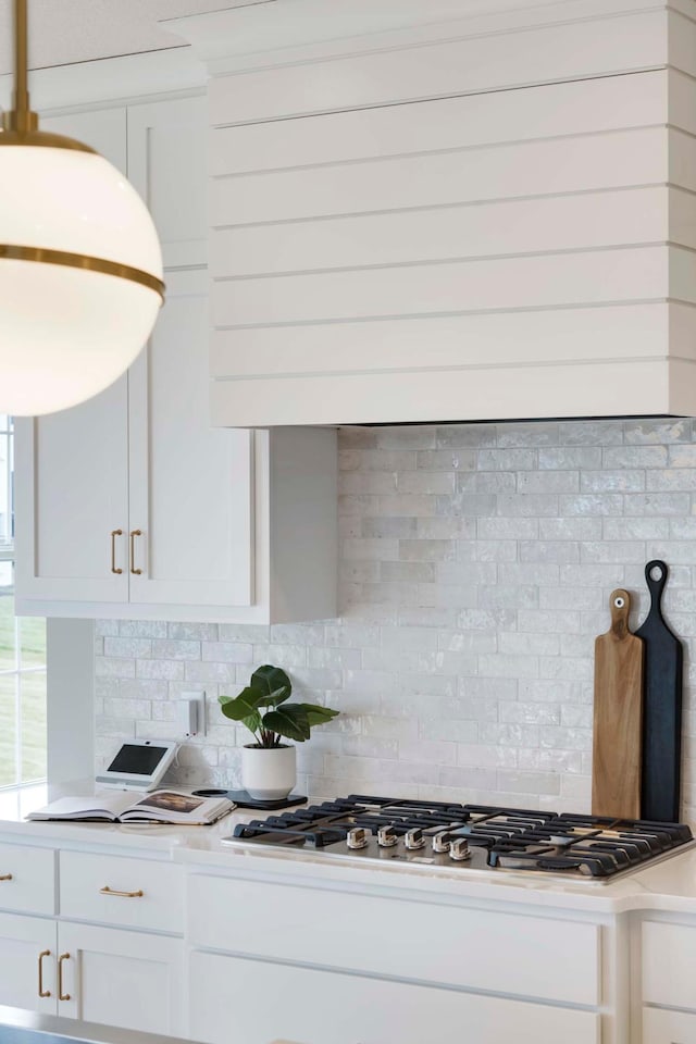 room details featuring white cabinets, backsplash, and stainless steel gas cooktop