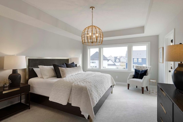 carpeted bedroom with a notable chandelier and a tray ceiling