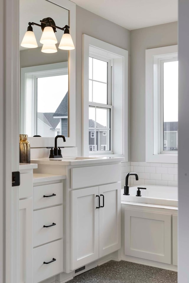 bathroom with vanity, a washtub, and a healthy amount of sunlight