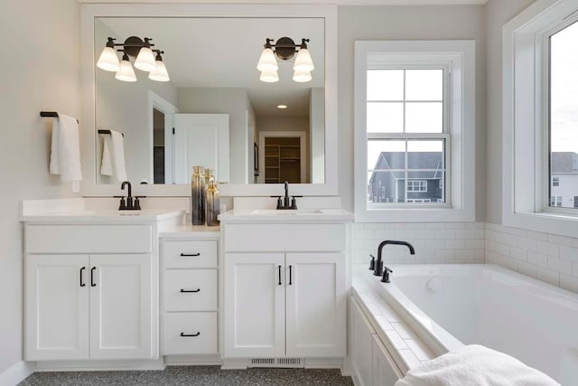 bathroom with tiled tub and double sink vanity