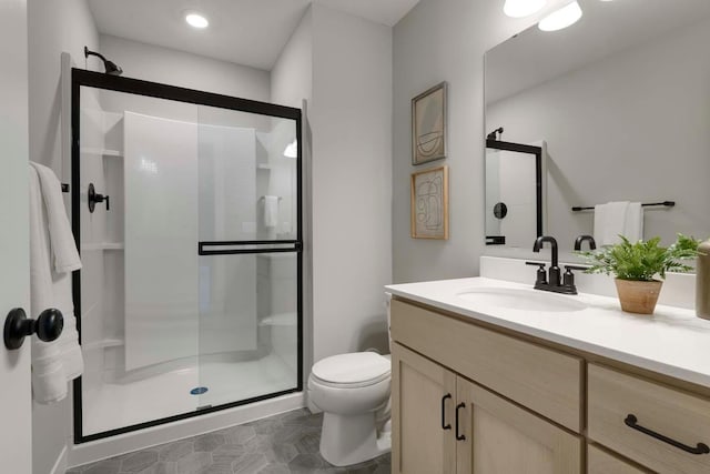 bathroom with a shower with shower door, vanity, tile patterned floors, and toilet