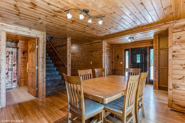 dining room with wood ceiling, wooden walls, and light wood-type flooring