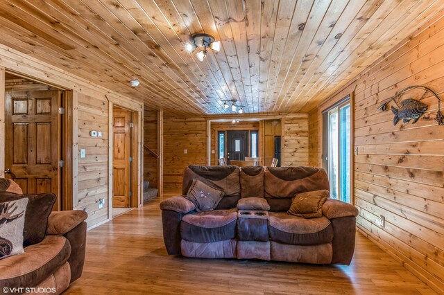 living room featuring light wood-type flooring, wooden walls, and wood ceiling