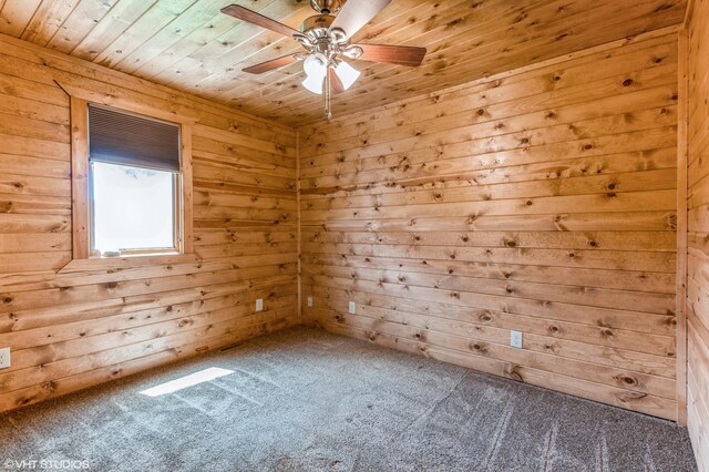 carpeted empty room featuring ceiling fan, wooden walls, and wood ceiling