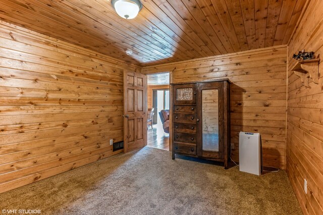 interior space featuring wood ceiling, wooden walls, and carpet