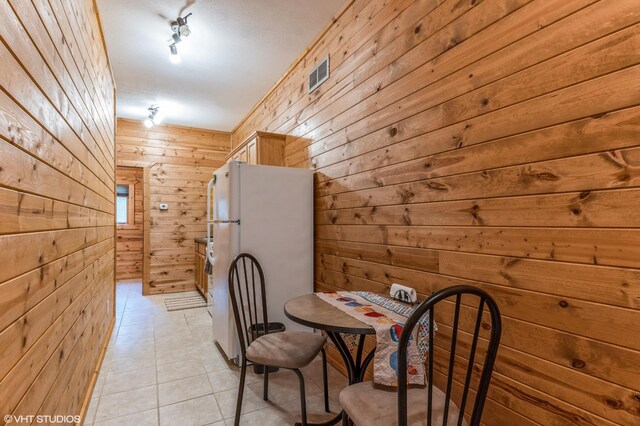 interior space with light tile patterned flooring and wooden walls