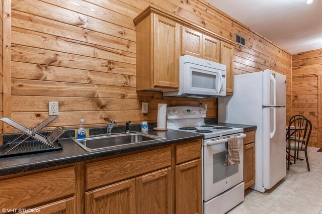 kitchen with sink, white appliances, and wood walls