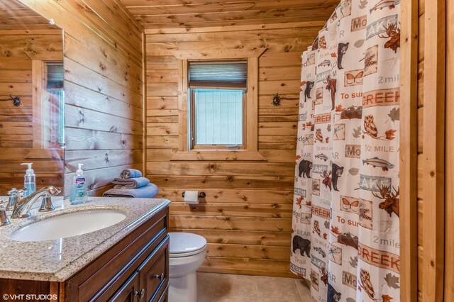 bathroom with tile patterned flooring, wooden walls, vanity, toilet, and walk in shower