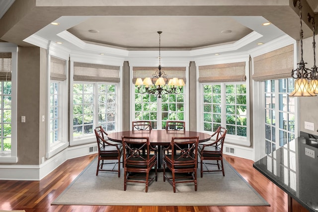 dining space with a raised ceiling, a notable chandelier, ornamental molding, and dark wood-type flooring