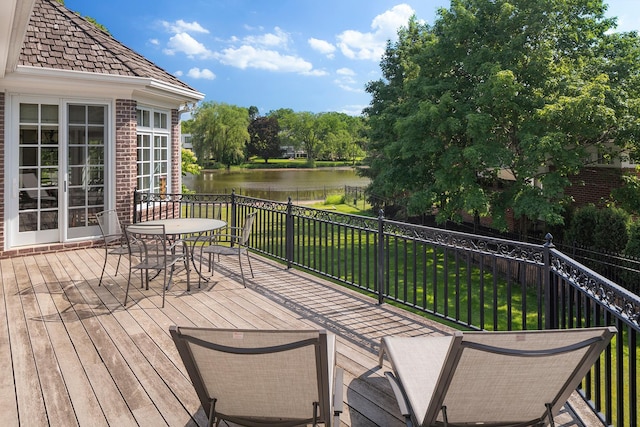 wooden deck with a water view and a lawn