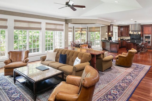 living room featuring ceiling fan with notable chandelier, dark wood-type flooring, crown molding, and vaulted ceiling