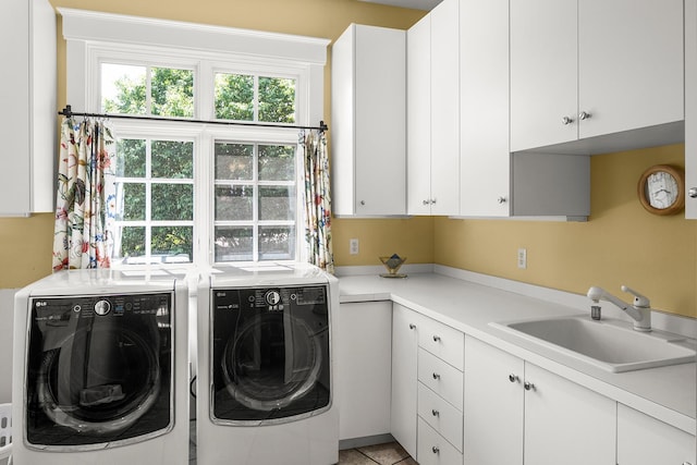 washroom with cabinets, light tile patterned floors, washing machine and clothes dryer, and sink