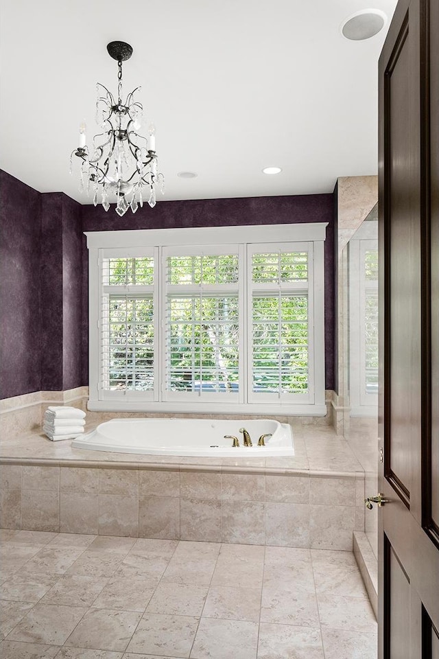 bathroom featuring a notable chandelier and tiled tub