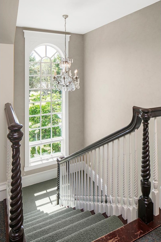 stairs with carpet, a healthy amount of sunlight, and a chandelier