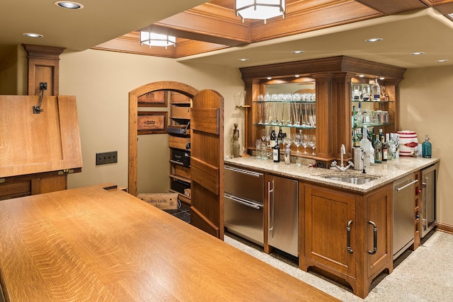 bar featuring light stone countertops, refrigerator, dishwasher, and sink