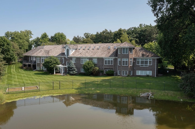 rear view of property featuring a water view, a pergola, and a yard