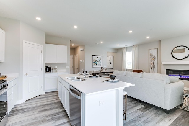 kitchen featuring white cabinetry, a kitchen island with sink, sink, and stainless steel dishwasher