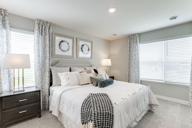 bedroom featuring light colored carpet and multiple windows