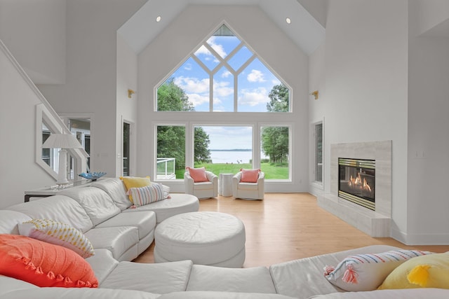 living room featuring light wood-type flooring, a high ceiling, and a tile fireplace