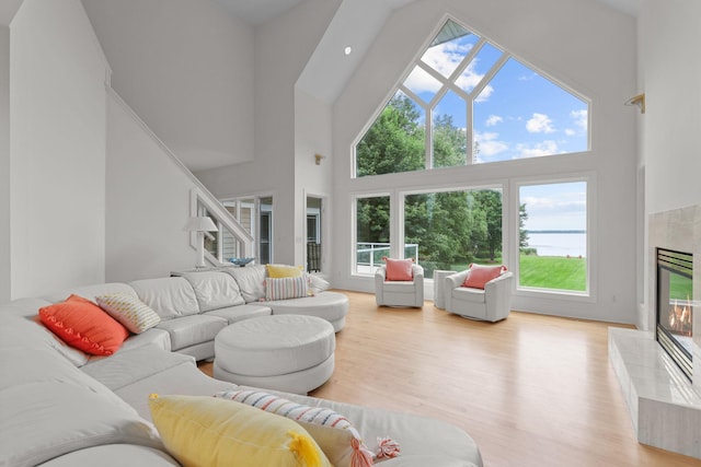 living room featuring light hardwood / wood-style flooring, a fireplace, and a towering ceiling