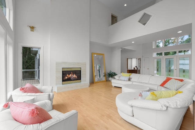 living room featuring a high end fireplace, wood-type flooring, and a high ceiling