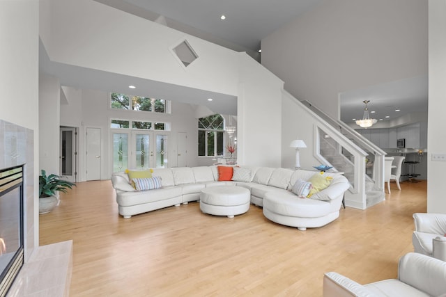 living room featuring a high ceiling, a tiled fireplace, and light wood-type flooring