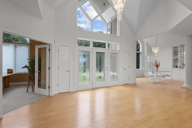 living room featuring light hardwood / wood-style floors, a high ceiling, and an inviting chandelier