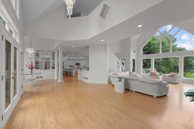 living room with an inviting chandelier, a towering ceiling, and light hardwood / wood-style flooring