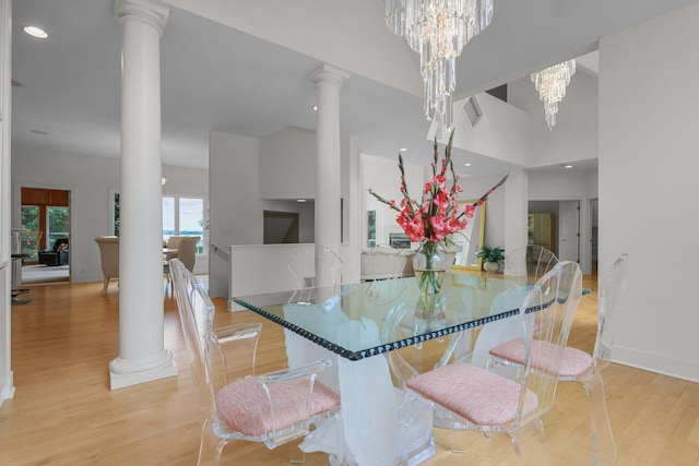 dining space with light wood-type flooring, an inviting chandelier, and ornate columns