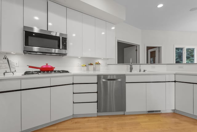 kitchen with white cabinets, light wood-type flooring, sink, and stainless steel appliances