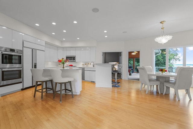 kitchen with white cabinetry, a kitchen breakfast bar, stainless steel appliances, and pendant lighting